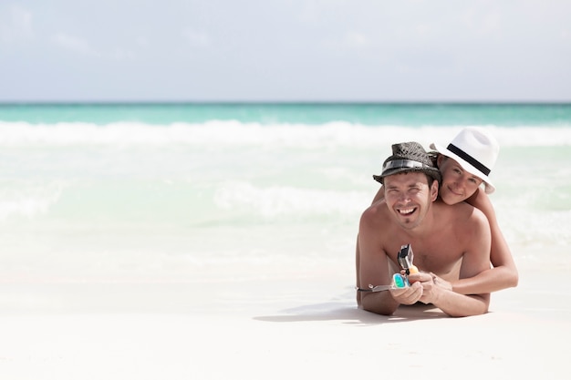 Foto gratuita coppie sorridenti felici a lungo tiro in spiaggia