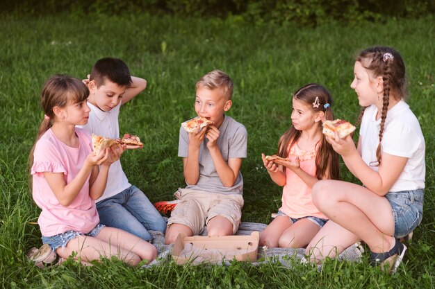 Long shot kids eating a slice of pizza