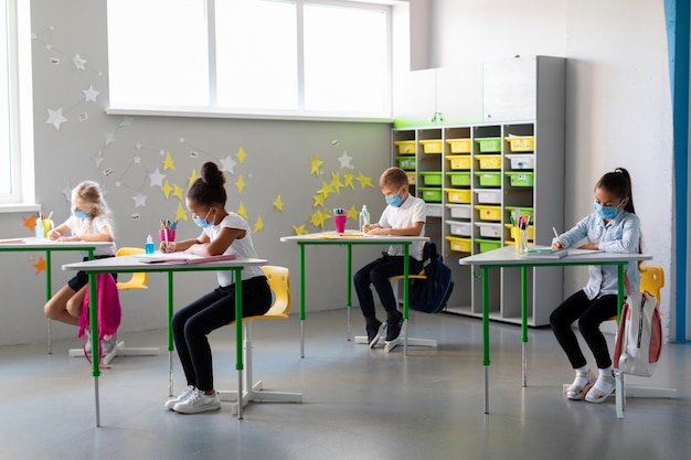 Long shot kids wearing medical masks in class