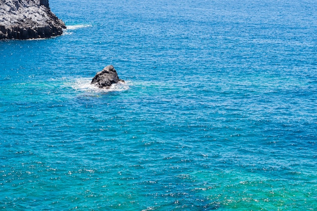 Free photo long shot lone rock in crystalline sea