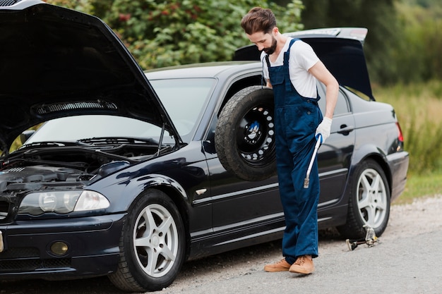 Free photo long shot of man holding spare tire