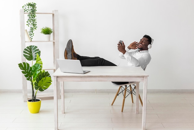 Free photo long shot of man sitting at the desk and listening to music