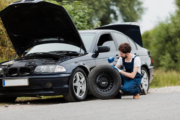 Free photo long shot of man swapping tire