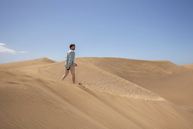 Long shot man with photo camera in the desert