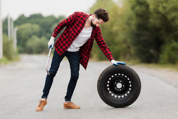 Long shot of man with wrench and tire