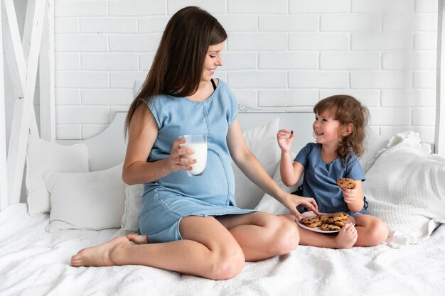 Long shot mother and daughter eating chocolate cookies 