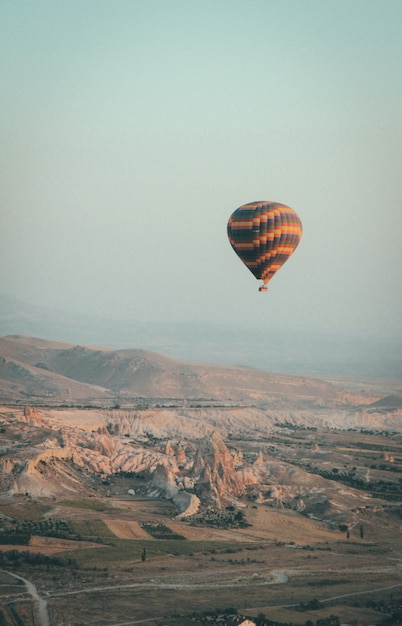 山の上の空に浮かぶ多色の熱気球のロングショット