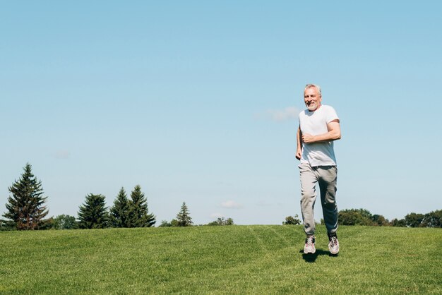 Long shot old man running in nature