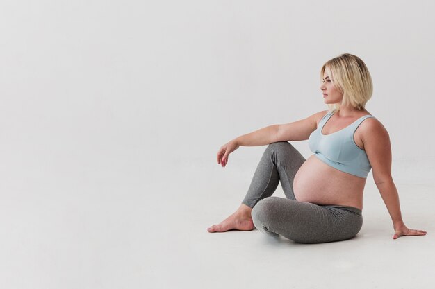 긴 총 임신 한 여자는 바닥에 앉아