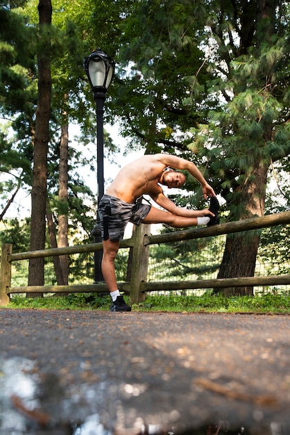 Long shot of runner stretching in park