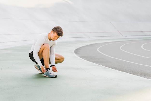 Long shot of runner tying his shoes