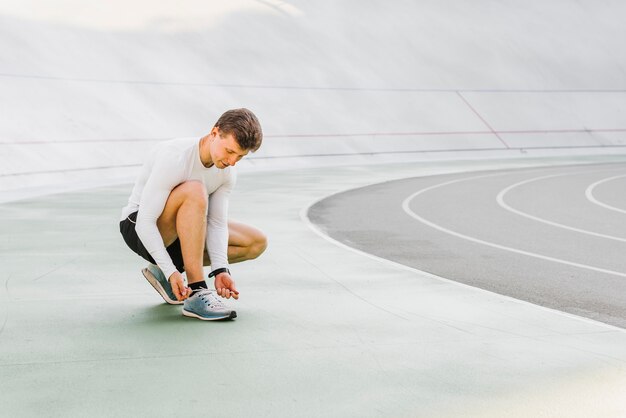 Long shot of runner tying his shoes