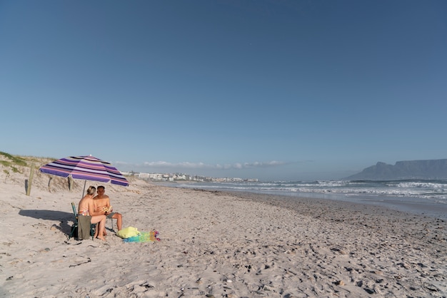 Free photo long shot senior couple chatting at beach