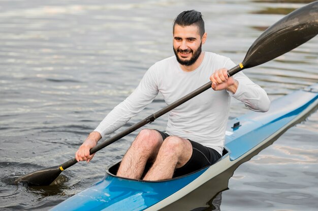 Long shot smiley man holding oar