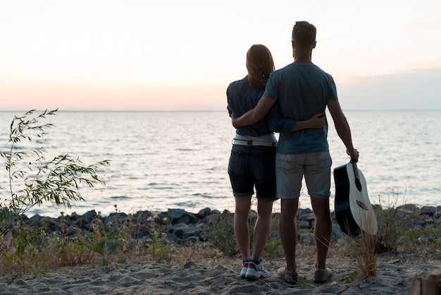 Long shot standing couple by the water