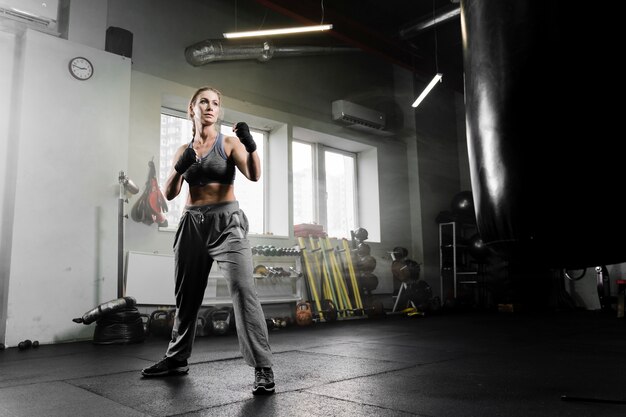 Long shot woman boxing in training center