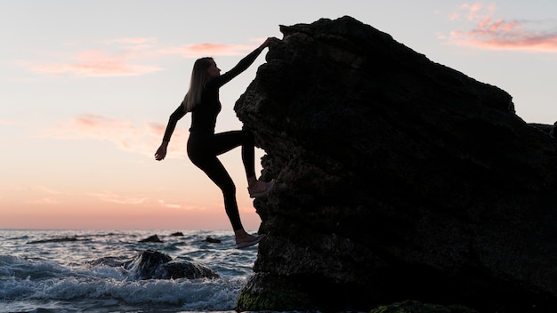 海の横の岩を登るロングショットの女性