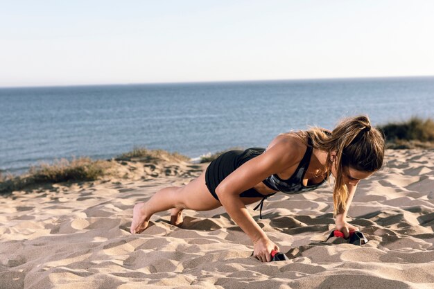 Long shot woman doing push ups on the beach
