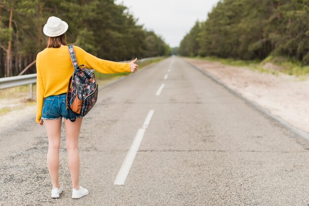 Long shot of woman hitchhiking