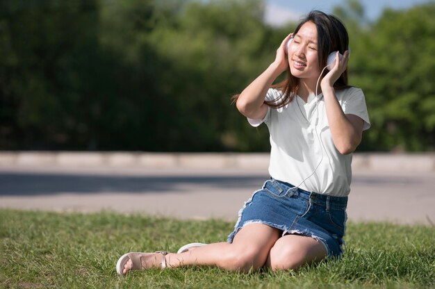 Long shot woman listening music through headphones