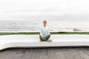 Free photo long shot woman meditating outdoors