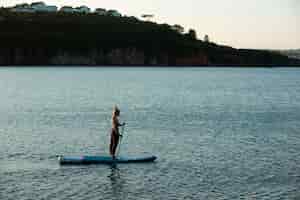 Free photo long shot woman paddleboarding