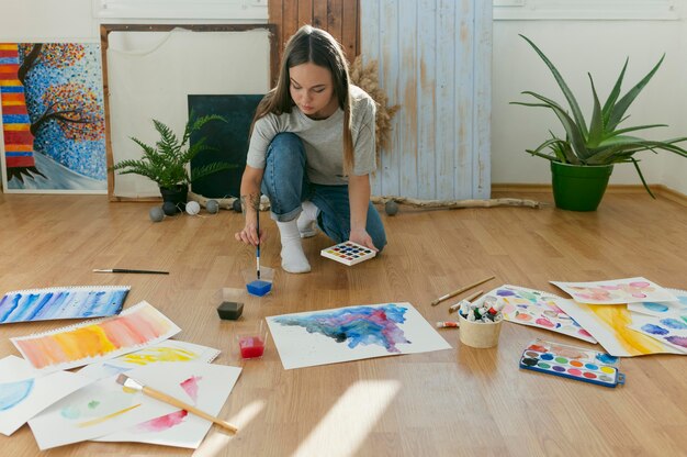 床に絵を描くロングショットの女性