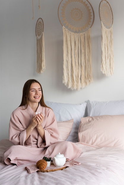 Long shot woman in robe staying in bed