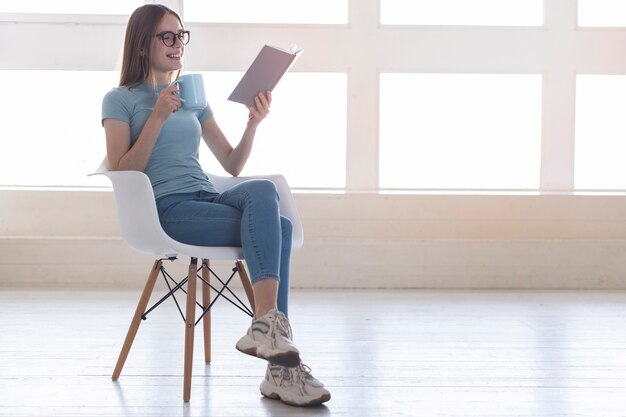 本を読みながら椅子に座ってロングショット女性