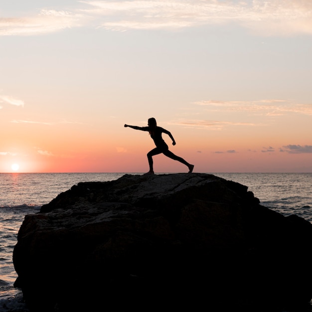 Long shot woman in sportswear scratching on a rock with copy space