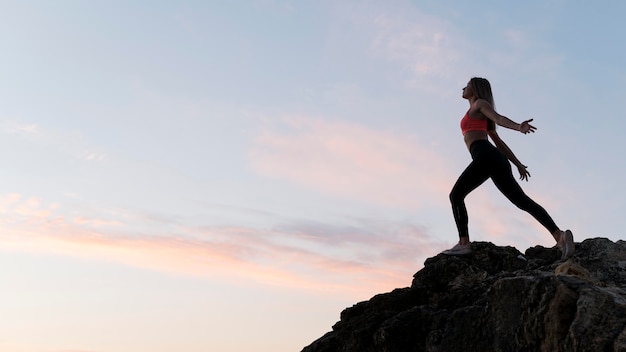 Long shot woman in sportswear standing on a coast with copy space