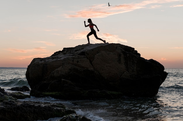 Long shot woman standing in a sports position on a rock