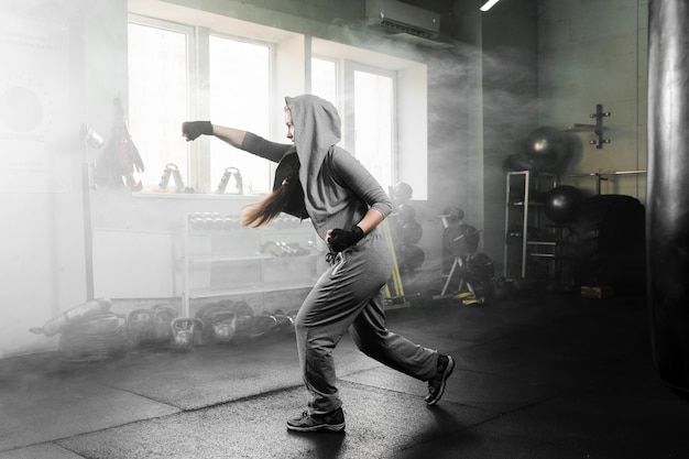 Long shot woman training in boxing center