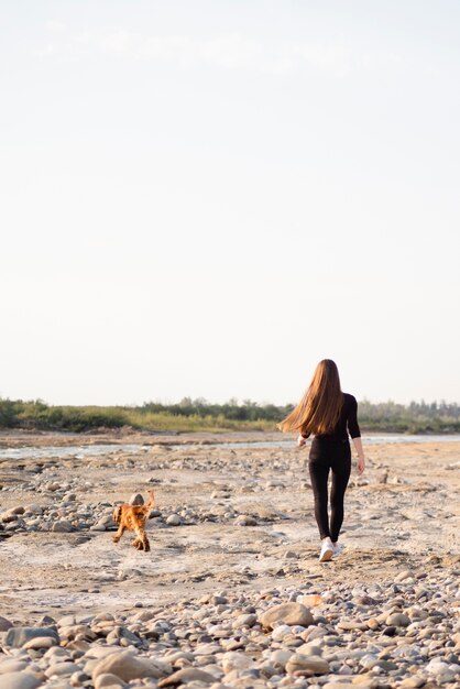彼女の犬と一緒に歩いているロングショット女性
