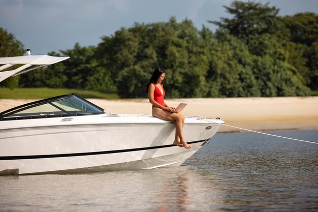 Long shot woman with laptop on boat