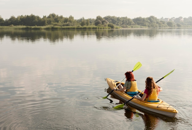 Long shot women rowing in kayak