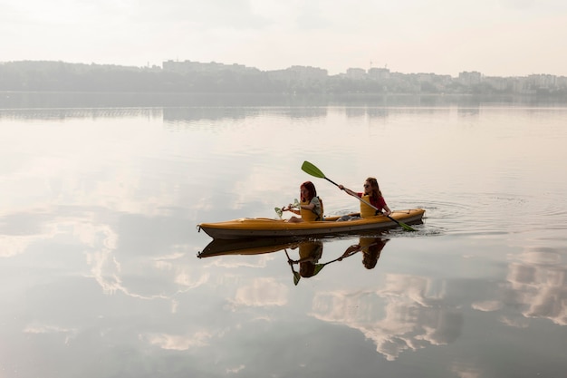 Long shot women rowing in kayak