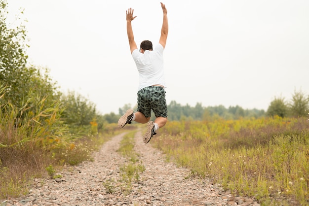 Free photo long shot of a young man jumping in nature