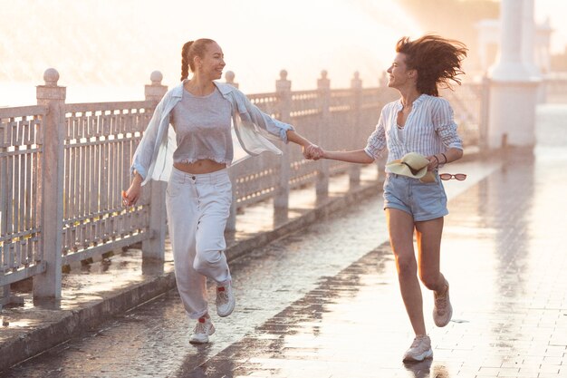 Long shot young women running and holding hands