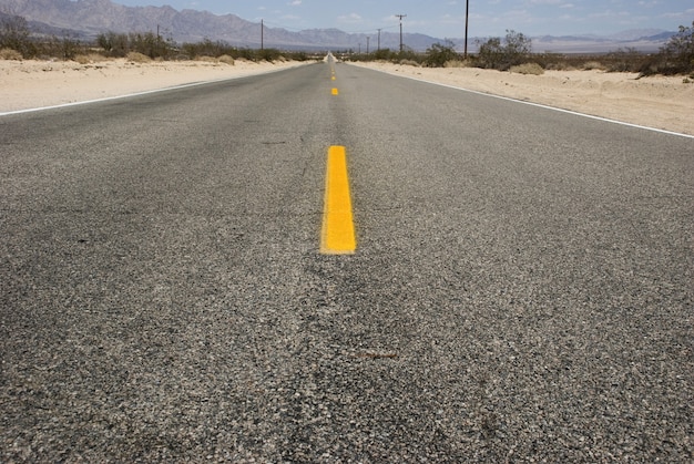 デスバレーの砂漠の風景を通る長くまっすぐなアスファルト道路