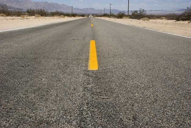 Длинная прямая асфальтированная дорога через пустынный ландшафт Долины Смерти