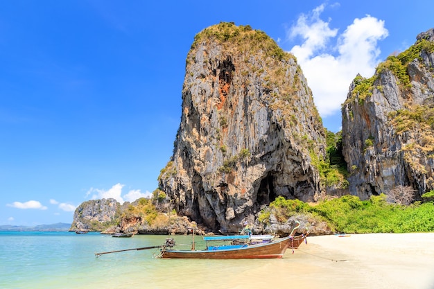 タイ、クラビのプラナンビーチにある石灰岩の崖と山のあるロングテールボートとターコイズブルーの透き通った海の水