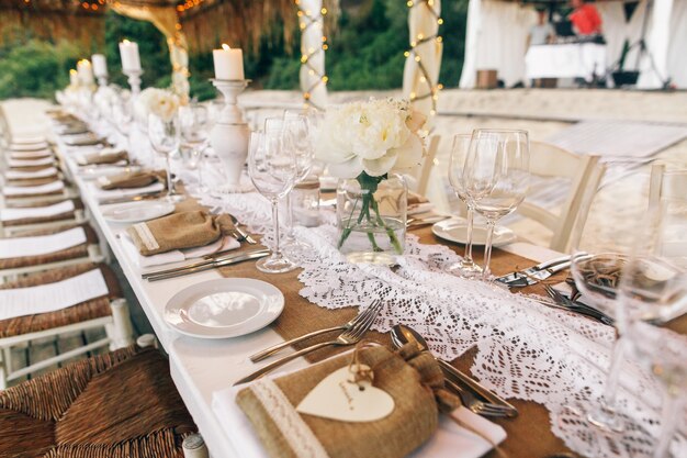 Long white table stands under white tents on sand beach