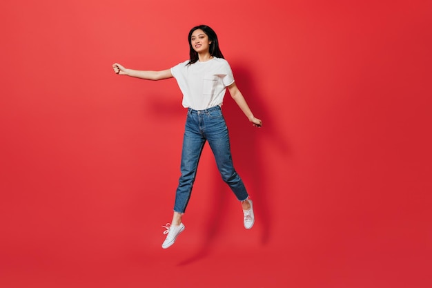 Longhaired woman in stylish outfit jumping on isolated background