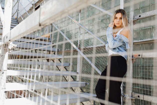 Look from behind a cage at stunning blonde standing in industrial building