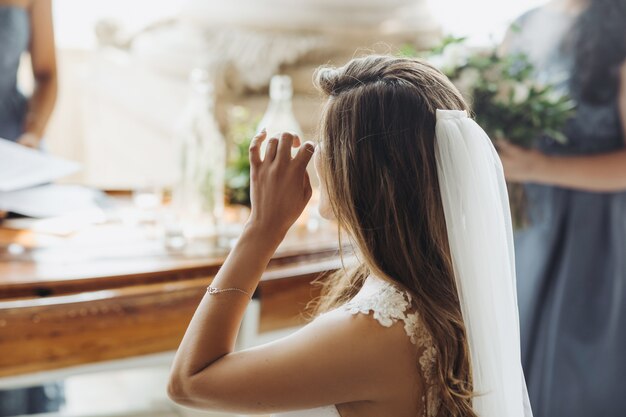 Look from behind at charming bride touching her eyes