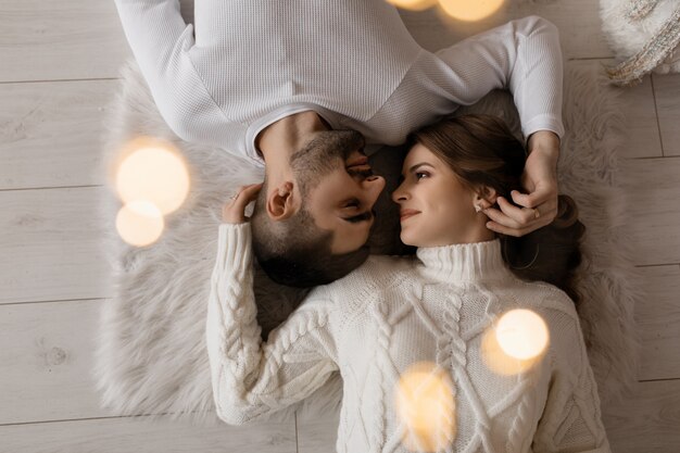Look from above at couple in white clothing lying on the floor
