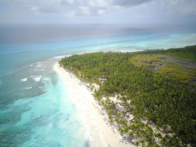 Look from above at turquoise water along golden beach somewhere in Dominican Republic