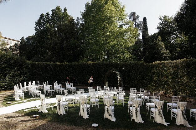 Look from behind at white chairs arranged for wedding ceremony