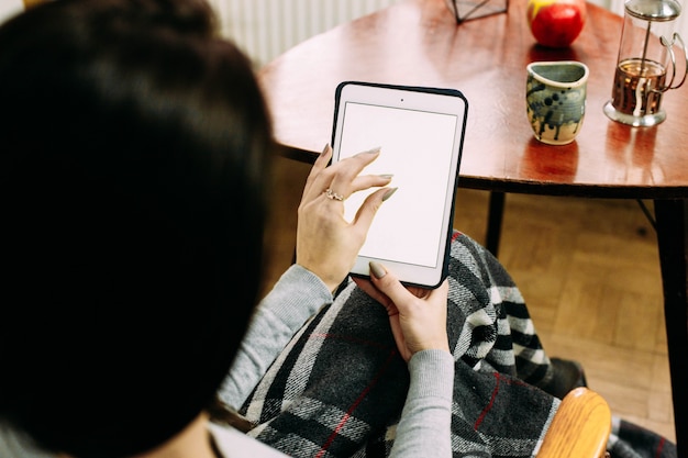 Free photo look from behind woman's shoulder at ipad in her arms